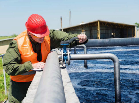 Worker inspecting water treatment plant pipes.