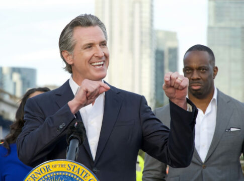 Smiling man giving a speech at an outdoor event.
