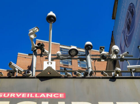 Array of security cameras mounted above a building facade under a clear blue sky