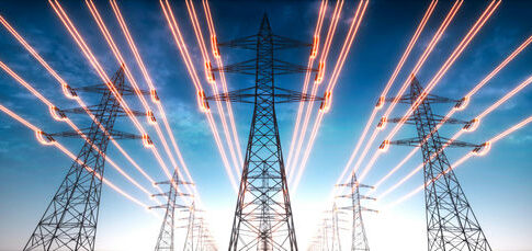 High-voltage transmission towers with glowing power lines at dusk