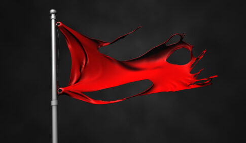 A tattered red flag waving on a pole against a dark background