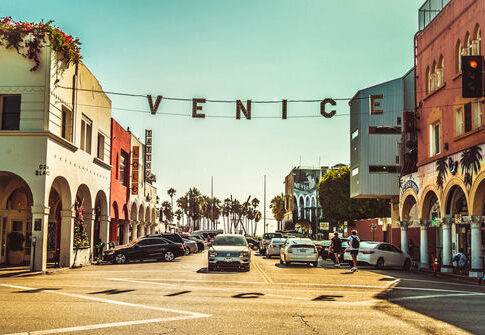 Venice Beach street with sign over road, sunny day.