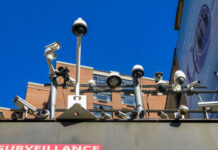 SECRET Dorm SPY GRID Stuns CAMPUS Array of security cameras mounted above a building facade under a clear blue sky