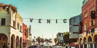 Venice Beach street with sign over road, sunny day.