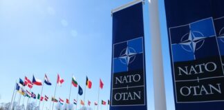 NATO flags displayed at the headquarters under a clear blue sky